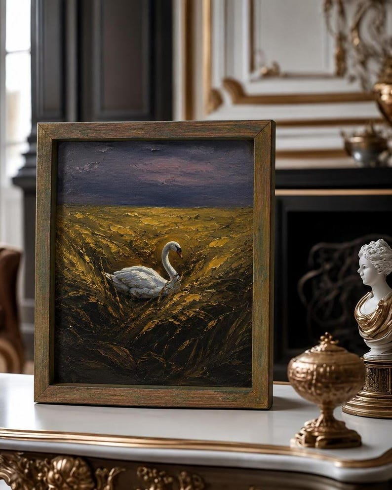 May include: An oil painting in a wooden frame shows a white swan in golden reeds beneath a dusky sky. The frame has a distressed, antique finish. The artwork is displayed on a white surface. The painting evokes a sense of serenity and natural beauty.