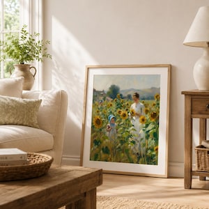 Puede incluir: Una impresi&oacute;n art&iacute;stica enmarcada representa a una mujer y un ni&ntilde;o en un campo de girasoles. La obra de arte tiene un marco de madera clara y se exhibe en un sal&oacute;n luminoso. La habitaci&oacute;n incluye un sof&aacute; beige, una mesa de centro de madera y una mesa auxiliar.