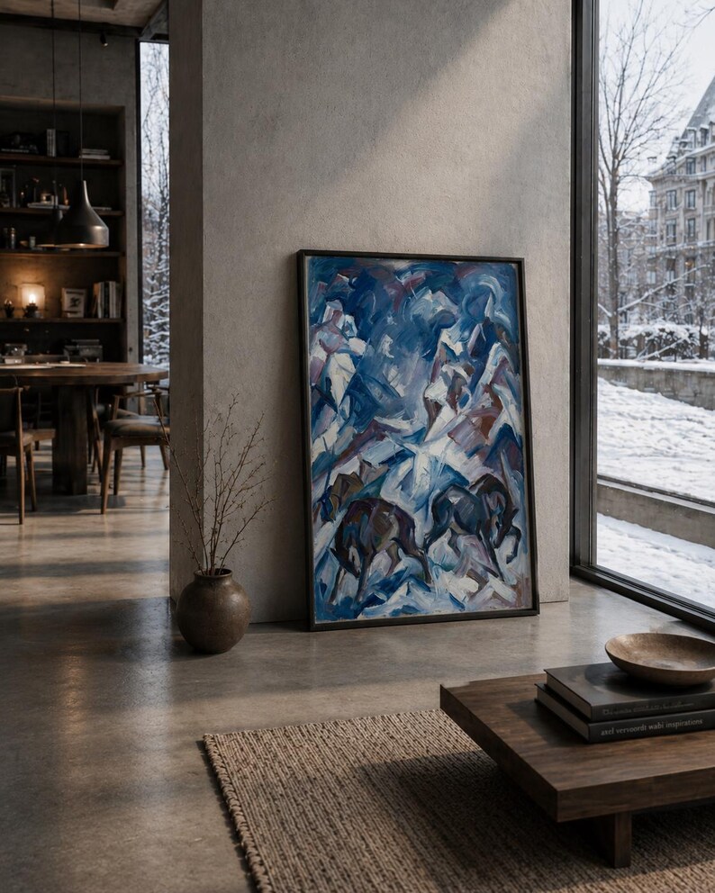 K&ouml;nnte beinhalten: Abstrakte Malerei von Pferden in einer verschneiten Landschaft. Das Kunstwerk hat einen dunklen Rahmen und eine Palette aus Blau-, Wei&szlig;- und Braunt&ouml;nen. Das Gem&auml;lde wird in einem modernen Wohnraum mit neutralem Farbschema ausgestellt.