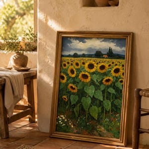 May include: A framed painting of a sunflower field with a gold-colored frame. The sunflowers are in full bloom with yellow petals and dark brown centers. The painting is leaning against a beige wall, with a glimpse of a rustic interior.