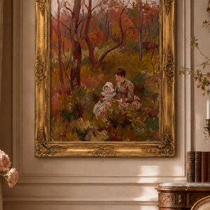 May include: A framed oil painting depicting a woman and child in a forest setting. The artwork features a gold ornate frame and a color palette of reds, greens, and browns. The painting captures a serene moment in nature.