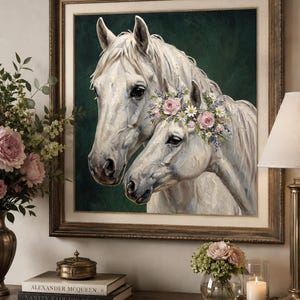 Op de afbeelding: Een ingelijst schilderij van twee witte paarden, waarvan &eacute;&eacute;n versierd met een bloemenkrans. Het kunstwerk heeft een donkergroene achtergrond en wordt gepresenteerd in een goudkleurige lijst. Het schilderij is een portret van de paarden, met de nadruk op hun hoofden en halzen.