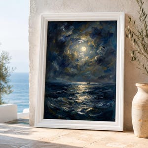 May include: A framed oil painting depicts a moonlit seascape. The artwork features a bright full moon illuminating dark, swirling clouds and the ocean waves. The painting is set in a white frame and leans against a stone wall.