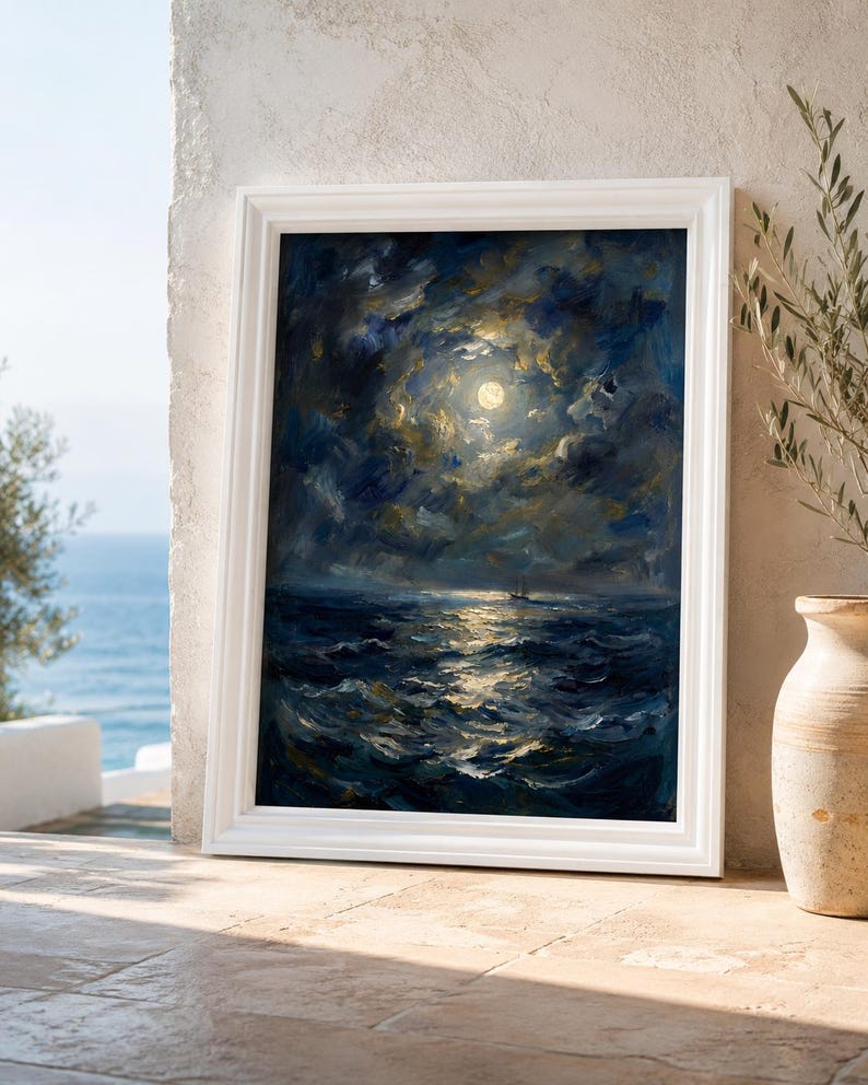 May include: A framed oil painting depicts a moonlit seascape. The artwork features a bright full moon illuminating dark, swirling clouds and the ocean waves. The painting is set in a white frame and leans against a stone wall.