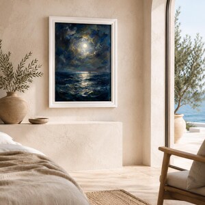 May include: A framed oil painting depicts a moonlit seascape with dark blue waves and a bright moon surrounded by clouds. The painting is in a white frame, hanging on a beige wall. The room has a neutral color palette, with a view of the ocean through an arched doorway.