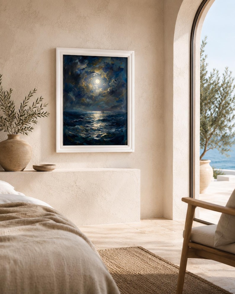 May include: A framed oil painting depicts a moonlit seascape with dark blue waves and a bright moon surrounded by clouds. The painting is in a white frame, hanging on a beige wall. The room has a neutral color palette, with a view of the ocean through an arched doorway.