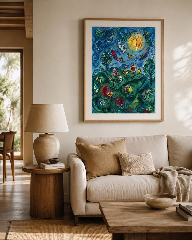 May include: A framed artwork depicting a colourful landscape scene. The painting shows a bright yellow sun, figures, flowers, and trees against a blue backdrop. The artwork is displayed above a beige sofa with brown cushions and a wooden coffee table.
