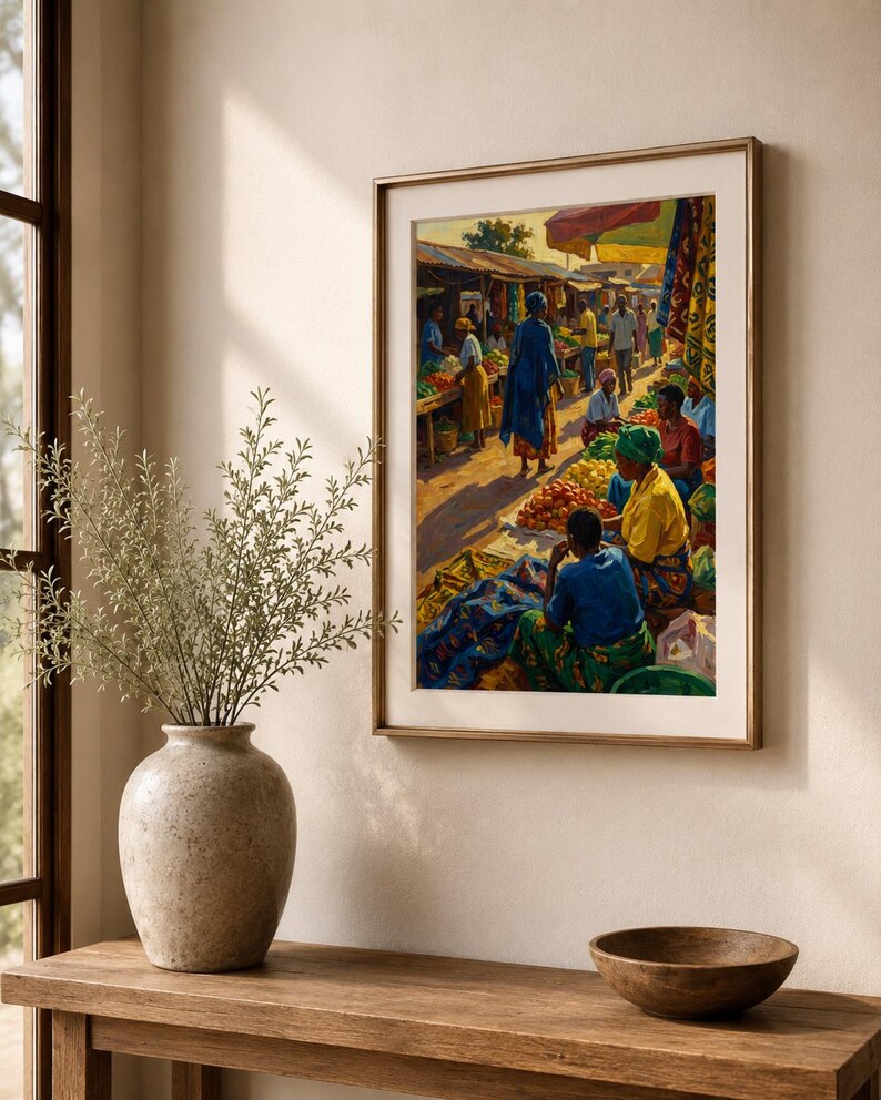 May include: A framed print showing a bustling market scene with figures in bright attire. The artwork features stalls laden with produce, illuminated by sunlight. The frame is gold-toned, and the print is displayed on a neutral wall.