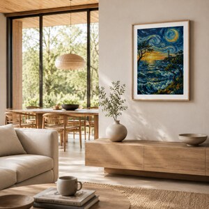 Op de afbeelding: Een ingelijste kunstdruk met een kustlandschap met een vuurtoren onder een wervelende nachthemel. Het kunstwerk heeft een levendig kleurenpalet van blauw, geel en oranje, met een houten lijst. De print wordt gepresenteerd in een moderne woonkamer.