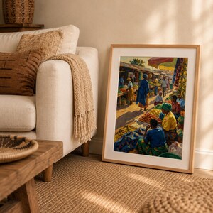May include: A framed print showing a bustling outdoor market. The artwork displays people in bright clothing, stalls laden with produce, and a sunny ambiance. The frame is a light wood colour.