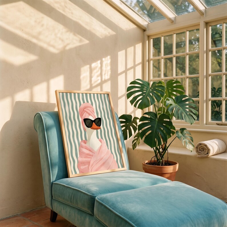 May include: A framed wall art print featuring a white duck wearing a pink towel wrap on its head and body, paired with black sunglasses. The background consists of vertical teal and white wavy stripes, all contained within a light wood frame.