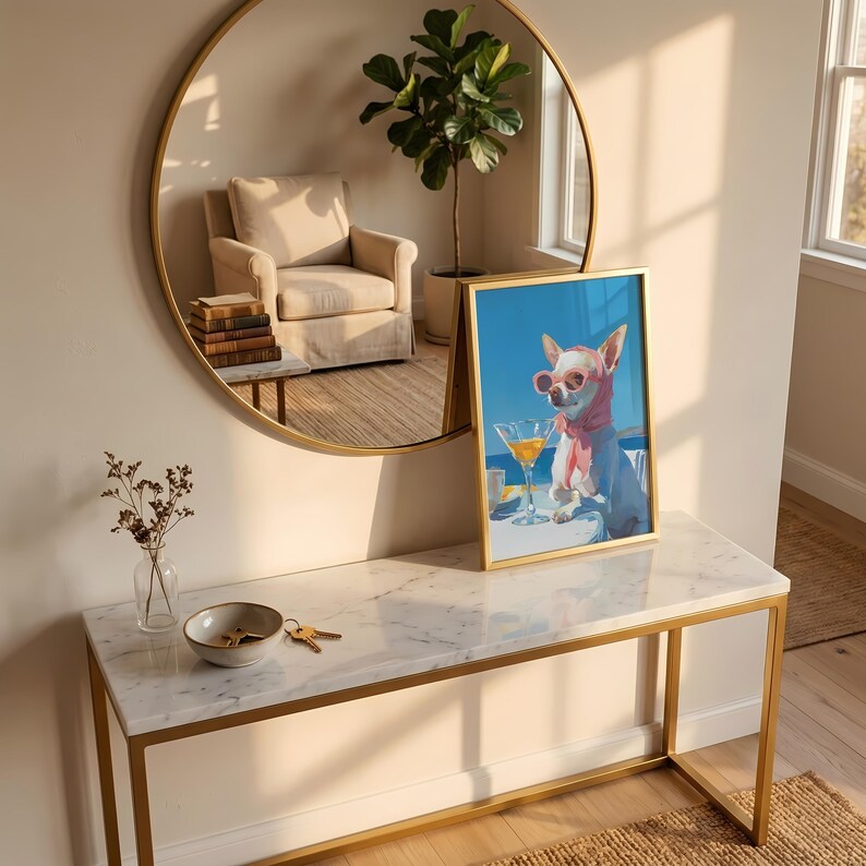 Puede incluir: Una impresi&oacute;n art&iacute;stica enmarcada que presenta un chihuahua con gafas de sol y una bufanda rosa, disfrutando de un c&oacute;ctel. La obra de arte est&aacute; ambientada sobre un fondo de cielo azul. La impresi&oacute;n se exhibe sobre una consola con tapa de m&aacute;rmol y marco dorado.