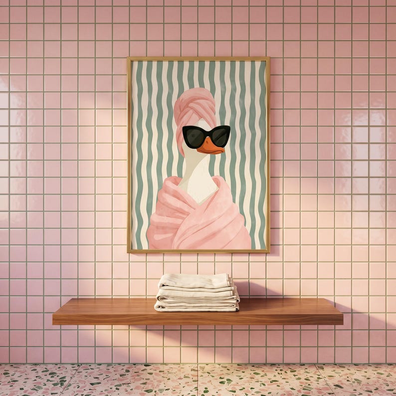 May include: A rectangular wall art print featuring a white duck wearing a pink towel wrapped around its head and body, paired with black cat-eye sunglasses. The background consists of vertical wavy teal and white stripes in a wooden frame.