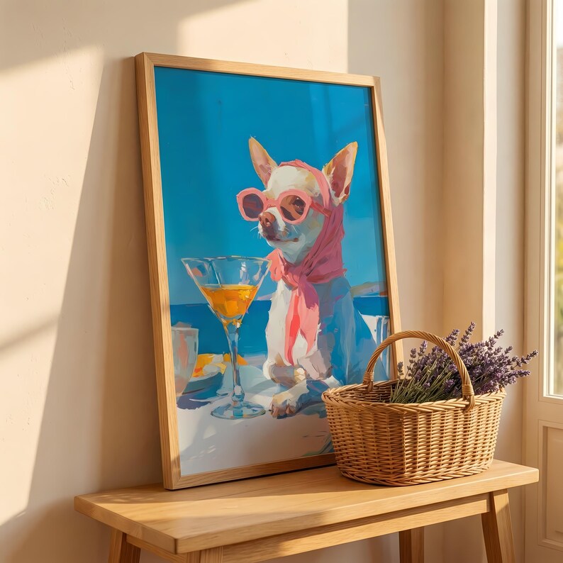 Puede incluir: Una impresi&oacute;n art&iacute;stica enmarcada representa un chihuahua con gafas de sol y bufanda rosas, disfrutando de un c&oacute;ctel. El fondo es un cielo azul brillante y un oc&eacute;ano. Una cesta de mimbre con lavanda est&aacute; sobre una mesa de madera.