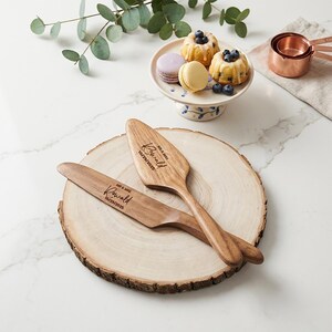 Pu&ograve; includere: Set di coltello e server per torte in legno con nomi e data incisi su una fetta di legno. Il set &egrave; vicino a un piccolo alzatina per torte con mini torte e macaron. Sono visibili anche misurini in rame.