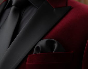 May include: A close-up of a formal suit jacket in a deep burgundy velvet. The jacket features black satin lapels, a black tie, and a black pocket square. The suit is a classic style, suitable for formal events.