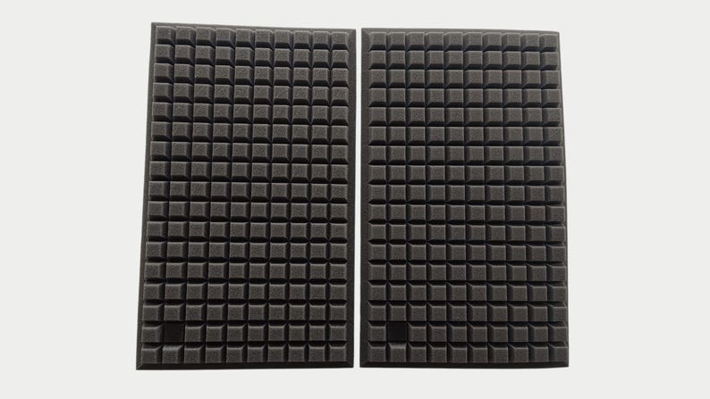 May include: Two rectangular black acoustic foam panels with a grid-like pattern of small, square protrusions. The panels are side by side against a white background, designed for sound absorption in a studio or home theater.