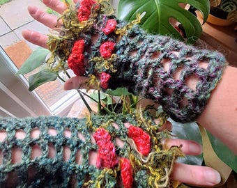 May include: Handmade crochet fingerless gloves in shades of green, purple, and yellow, adorned with red accents. The openwork design allows for flexibility and breathability. These unique gloves are a statement piece, perfect for adding a touch of artistry to any outfit.