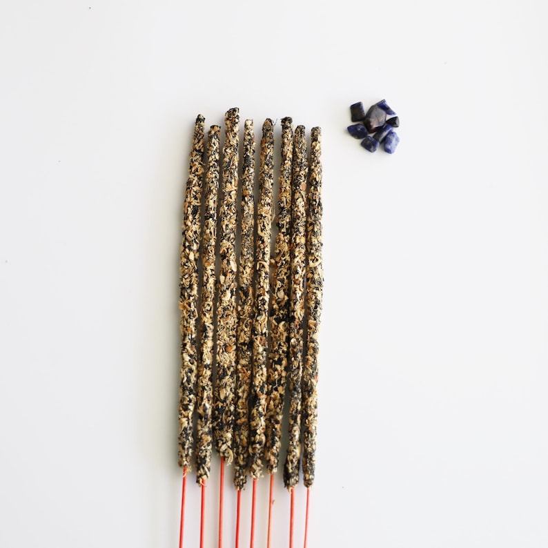 Incense sticks with Lapis Lazuli chips nearby on a white surface.