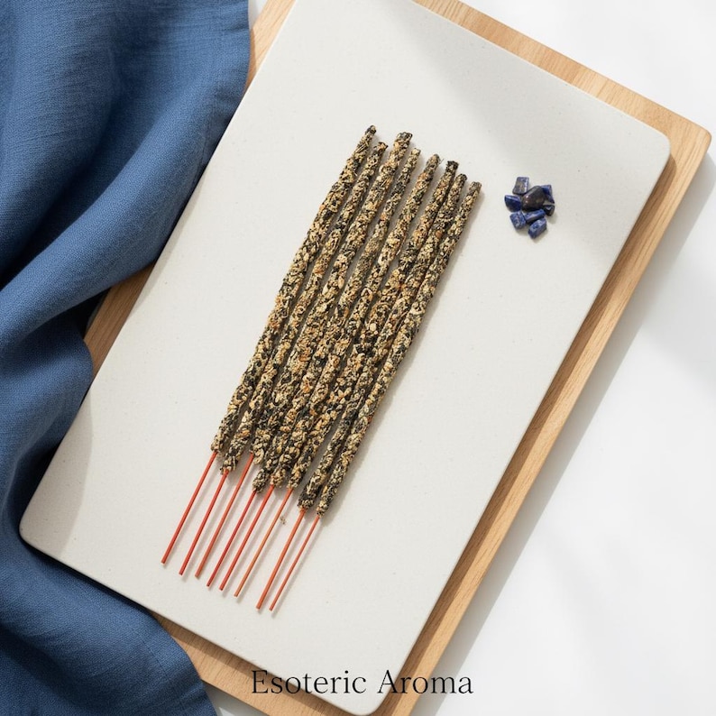 Incense sticks on a tile on a white surface with a blue cloth nearby