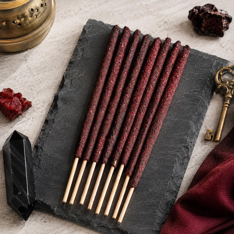 Incense sticks on a dark slate surface, surrounded by decorative items.