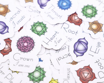 May include: A set of seven chakra stickers with colorful symbols and corresponding names and affirmations. The stickers are printed on white paper with rounded edges. The chakras are Root, Sacral, Solar Plexus, Heart, Throat, Third Eye, and Crown.