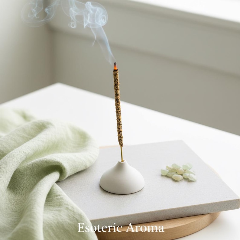 Incense stick with smoke on a white ceramic holder on a blue cloth
