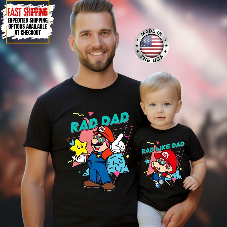 May include: Black t-shirts with matching "Rad Dad" and "Rad Like Dad" Mario-themed graphics. The adult shirt features Mario holding a star, while the child's shirt shows Mario in a similar pose. "Made in the USA" is printed on a circular badge.