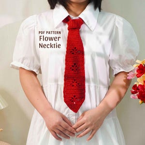 Puede incluir: Una corbata de flores de ganchillo roja brillante con un diseño floral, sobre una camisa blanca. El texto "PDF PATTERN Flower Necktie" es visible. Este accesorio hecho a mano es único.