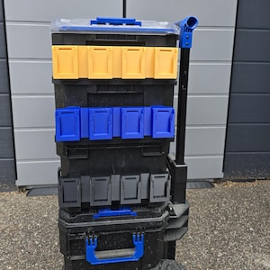 May include: A black rolling tool chest with multiple compartments and blue and yellow accents. The tool chest has a clear top and a telescoping handle for easy transport. The compartments are secured with blue, yellow, and gray latches.