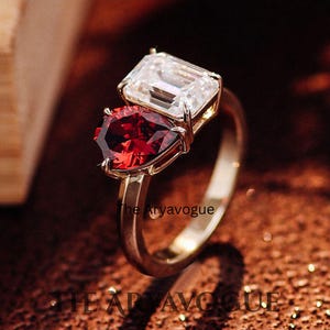 Anello di fidanzamento a due pietre con moissanite taglio smeraldo e rubino.