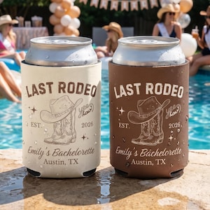 Puede incluir: Dos enfriadores de latas, uno crema y otro marrón, con el texto "LAST RODEO" y un gráfico de sombrero y bota de vaquero. El texto "Emily's Bachelorette, Austin, TX" también está impreso en los enfriadores. El año "2026" está impreso.