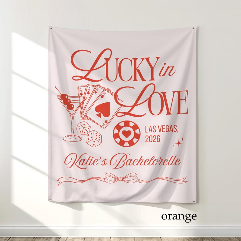 May include: A light pink banner with red text and graphics. The banner reads "Lucky in Love" with a martini glass, playing cards, dice, and a casino chip. The text "Las Vegas, 2026" and "Katie's Bachelorette" are also included.