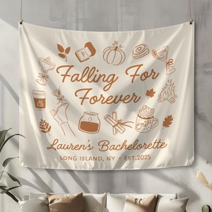 May include: Cream-colored tapestry with brown illustrations and text. The words "Falling For Forever" are in the center, with "Lauren's Bachelorette" below. The tapestry includes drawings of fall-themed items like pumpkins and leaves.