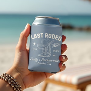 以下が含まれることがあります： 「Last Rodeo」の文字とカウボーイハットとブーツのグラフィックが描かれた、水色の缶クーラー。 「Emily's Bachelorette, Austin, TX」の文字も表示されています。 ビーチで人がクーラーを持っています。