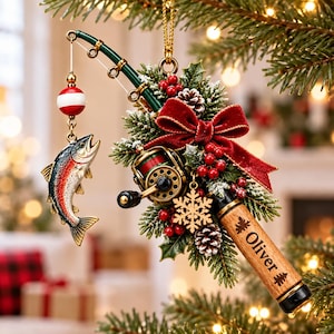 May include: A Christmas tree ornament shaped like a fishing rod with a green shaft, a gold reel, and a dangling trout. It features a red velvet bow, holly berries, pinecones, a gold snowflake charm, and a wooden handle engraved with the name Oliver.