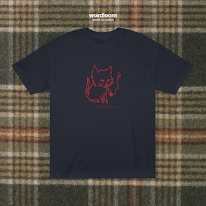 May include: Navy blue t-shirt featuring a red outline of a cat smoking a cigarette. The text "wordloom words on cotton" is at the top, and "the human experience" is below the cat illustration. The shirt is made of soft cotton.