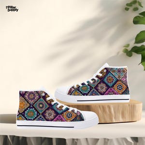 May include: High-top canvas sneakers with a colorful geometric pattern. The design features squares with floral and abstract motifs in shades of purple, orange, teal, and pink. The shoes have white laces and soles.