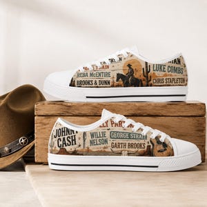 May include: Low-top canvas sneakers featuring a beige desert-themed print with illustrations of a cowboy on horseback, a guitar, and a cactus. The design includes the names of country music artists like Johnny Cash, Reba McEntire, and Luke Combs.