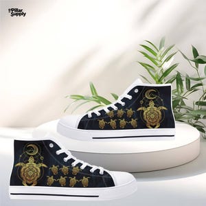 May include: High-top canvas sneakers with a navy blue background and a gold turtle design. The sneakers have white laces and soles. The design includes a large turtle with a crescent moon and smaller turtles.