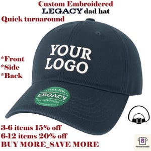 Può includere: Un cappello Legacy blu navy con testo ricamato bianco "YOUR LOGO". Il cappello ha una visiera curva e un'etichetta circolare verde e bianca. Il testo "Custom Embroidered LEGACY dad hat" è in alto.