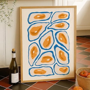 Op de afbeelding: Een ingelijste abstracte kunstprint met oranje en blauwe organische vormen op een crèmekleurige achtergrond. Het kunstwerk wordt gepresenteerd in een licht houten frame, leunend tegen een witte kast. Een fles wijn en een fruitmand staan in de buurt.