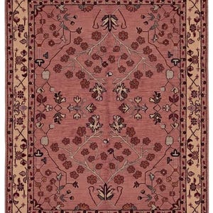 May include: A rectangular rug with a central field of dusty rose, adorned with floral and botanical patterns in shades of brown, beige, and green. The rug has a beige border with intricate designs and fringe.