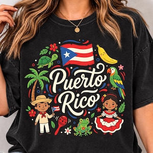 May include: A black t-shirt featuring a colourful graphic with the text Puerto Rico in white script. The design includes the Puerto Rican flag, a palm tree, a banana, a turtle, a parrot, a frog, a maraca, and two figures in traditional clothing.