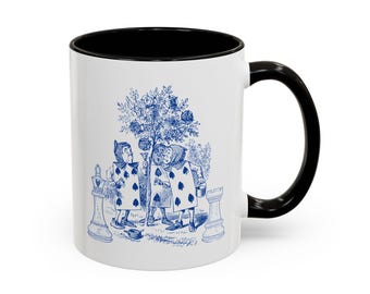May include: White ceramic mug with a black interior and handle. The mug features a blue illustration of characters from Alice in Wonderland, including playing card figures and a tree. A chess piece is also visible.