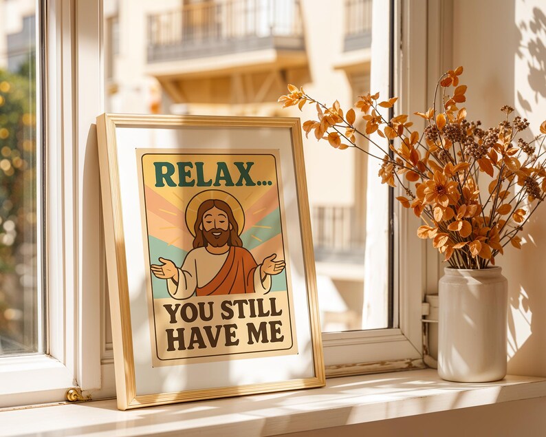 May include: A framed print with the text "RELAX... YOU STILL HAVE ME" featuring an illustration of Jesus with open arms. The artwork has a vintage aesthetic with a beige background and a gold frame. A vase of orange flowers sits nearby.