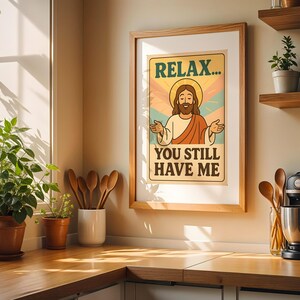May include: A framed poster with the text "RELAX... YOU STILL HAVE ME" and an illustration of Jesus. The poster is in a wooden frame and hangs on a wall above a wooden countertop. The kitchen has plants and wooden utensils.