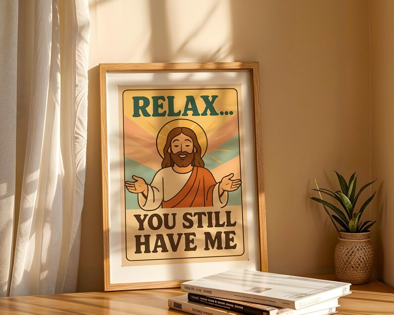 May include: Framed poster with a retro design featuring an illustration of Jesus with a halo, arms outstretched. The text reads "RELAX... YOU STILL HAVE ME" in a vintage font, set against a backdrop of pastel colors. The frame is made of light-colored wood.