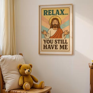 May include: A framed poster with the text "RELAX... YOU STILL HAVE ME" featuring an illustration of Jesus. A teddy bear sits on a wooden chair in front of a white wall. A small wooden shelf holds more teddy bears.