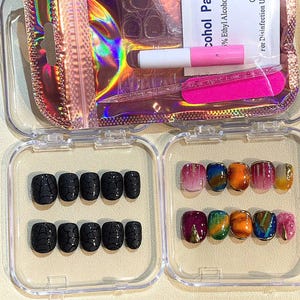 Puede incluir: Un juego de u&ntilde;as postizas en una caja de pl&aacute;stico transparente. Las u&ntilde;as presentan varios dise&ntilde;os, incluyendo patrones de telara&ntilde;a negros y arte abstracto colorido. Tambi&eacute;n se incluyen pegamento para u&ntilde;as y una lima de u&ntilde;as rosa.